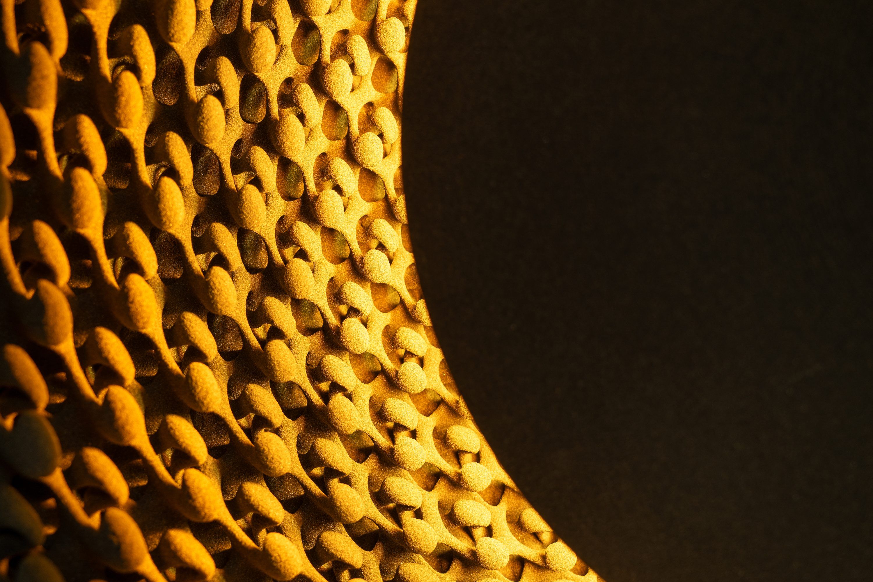 Detail van een wandlamp met een reliëf van kleine gouden vormen rond een donkere cirkel