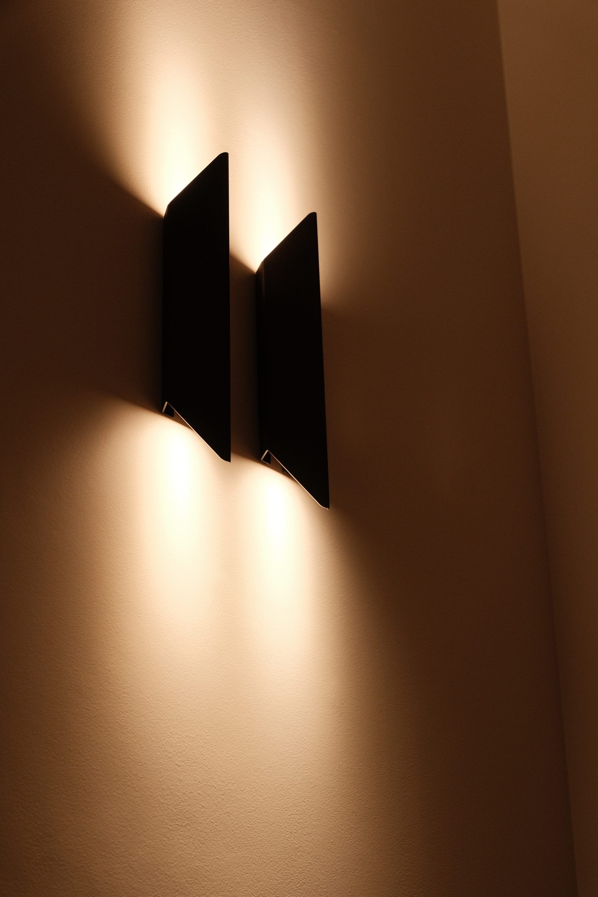 Twee wandlampen van zwart metaal die het licht omhoog en omlaag over de wand werpen
