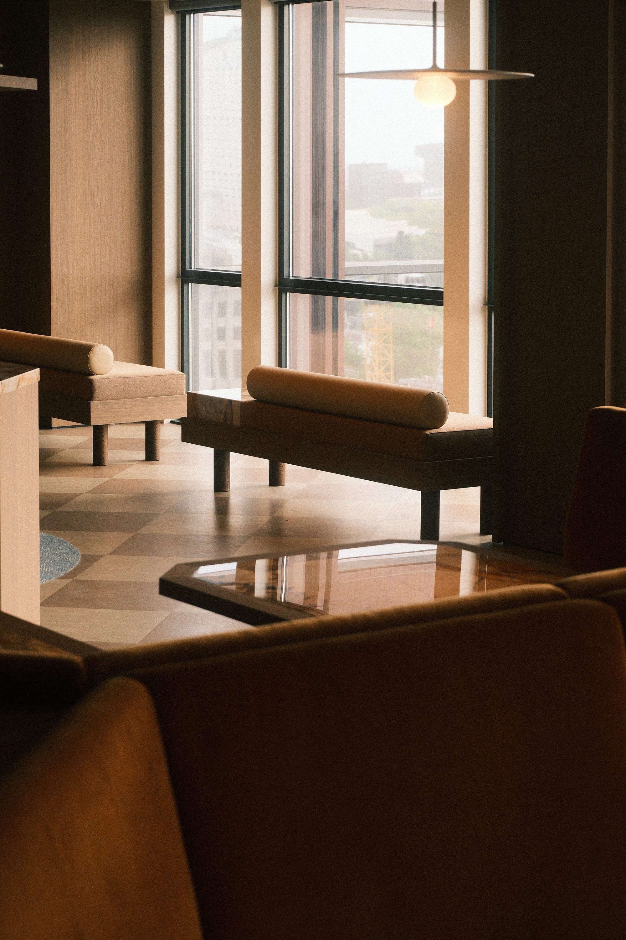 Loungehoek met lage banken voor een raam, onder een platte hanglamp