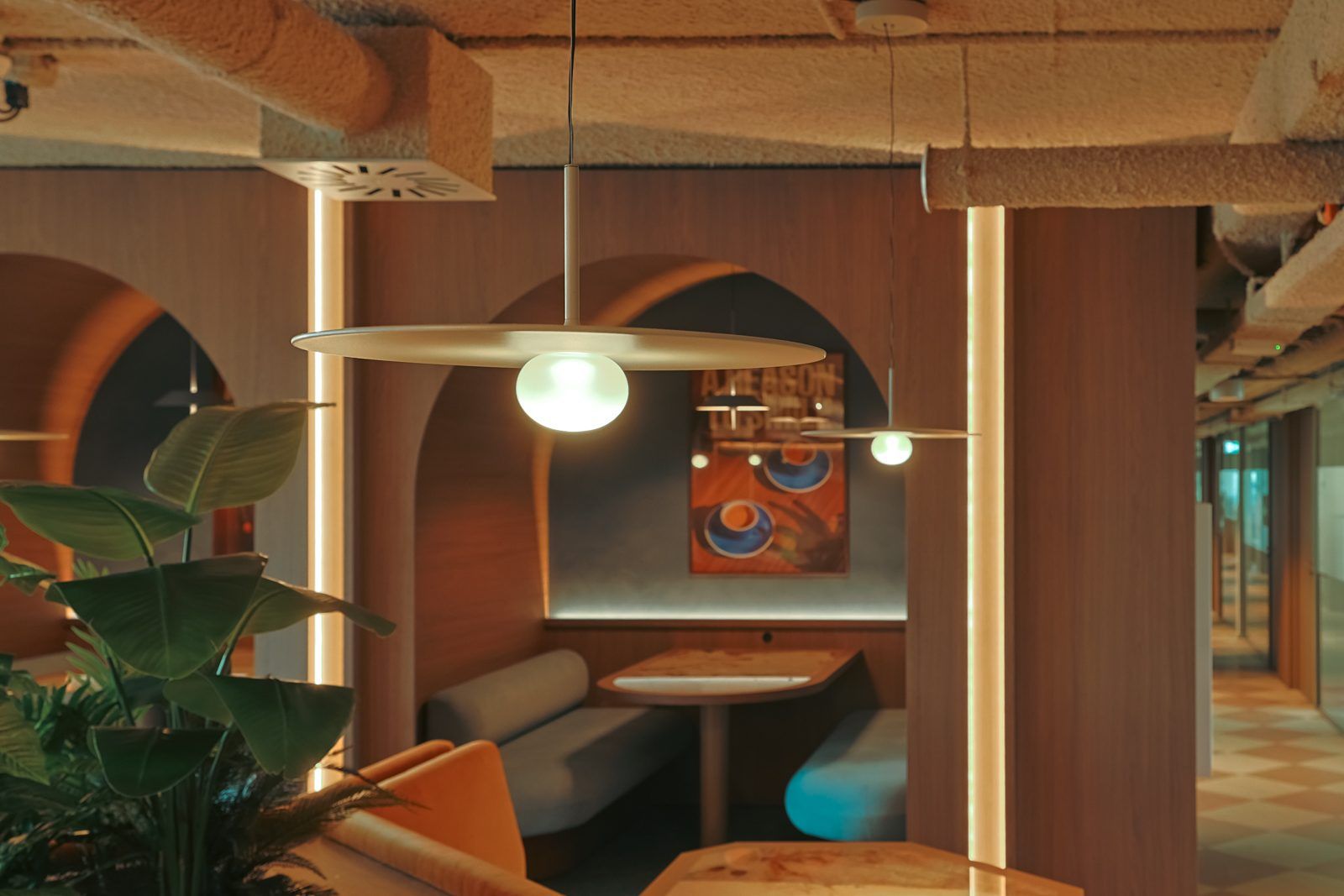 Zitnis in een boog met een glazen hanglamp boven de tafel, verlichte lijnen langs de houten zuilen en planten op de voorgrond